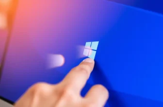 Finger touching Windows logo on a screen.
