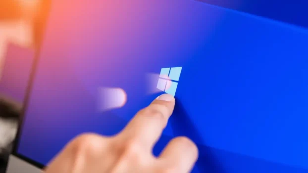 Finger touching Windows logo on a screen.