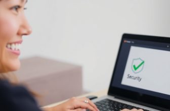 Woman smiling at laptop with security checkmark
